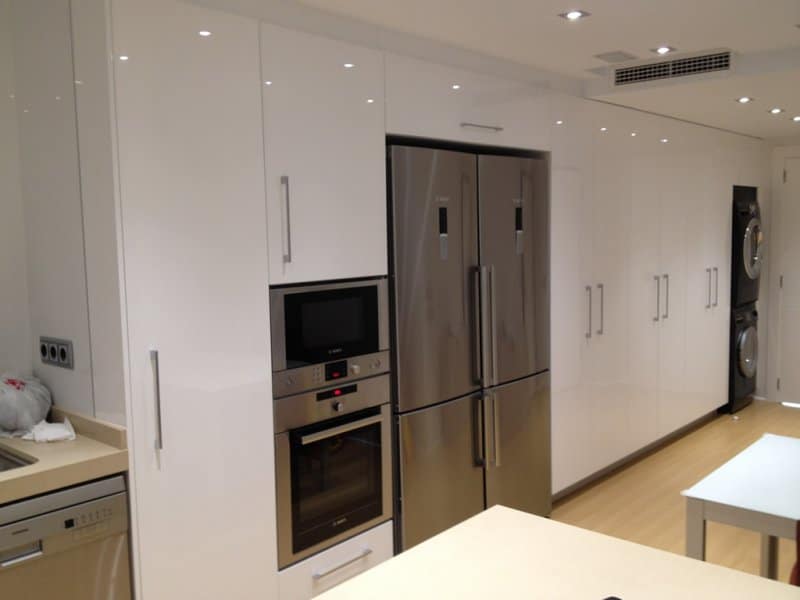 Cocina blanca con frigorífico americano y hornos en columna