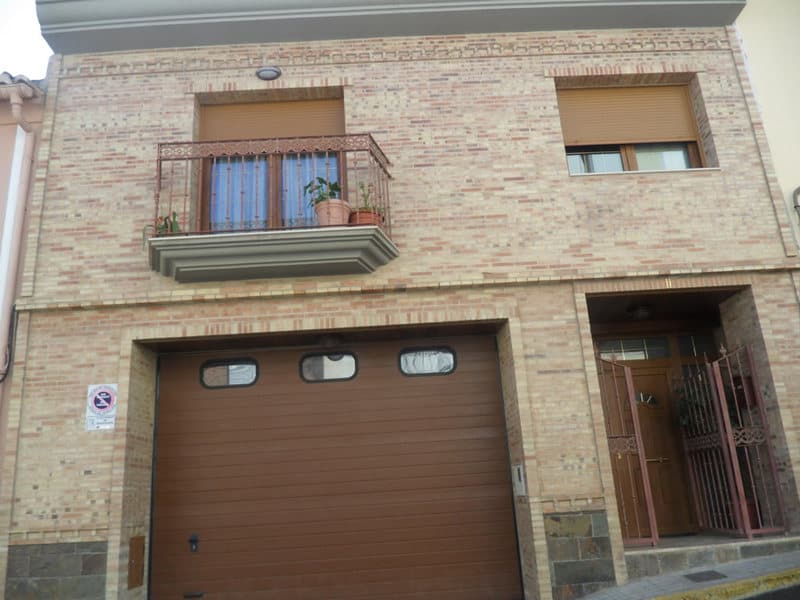 Fachada de ladrillo con balcón y puerta de garaje construida por Construcciones Bataller