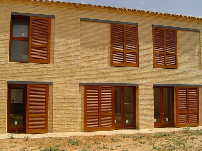 Fachada de ladrillo caravista con contraventanas de madera