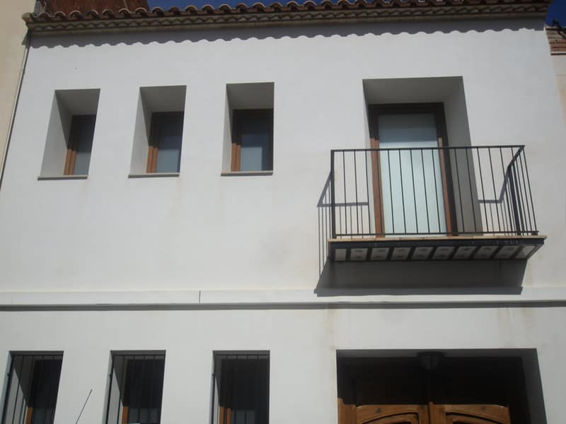 Fachada blanca rehabilitada con balcón de forja